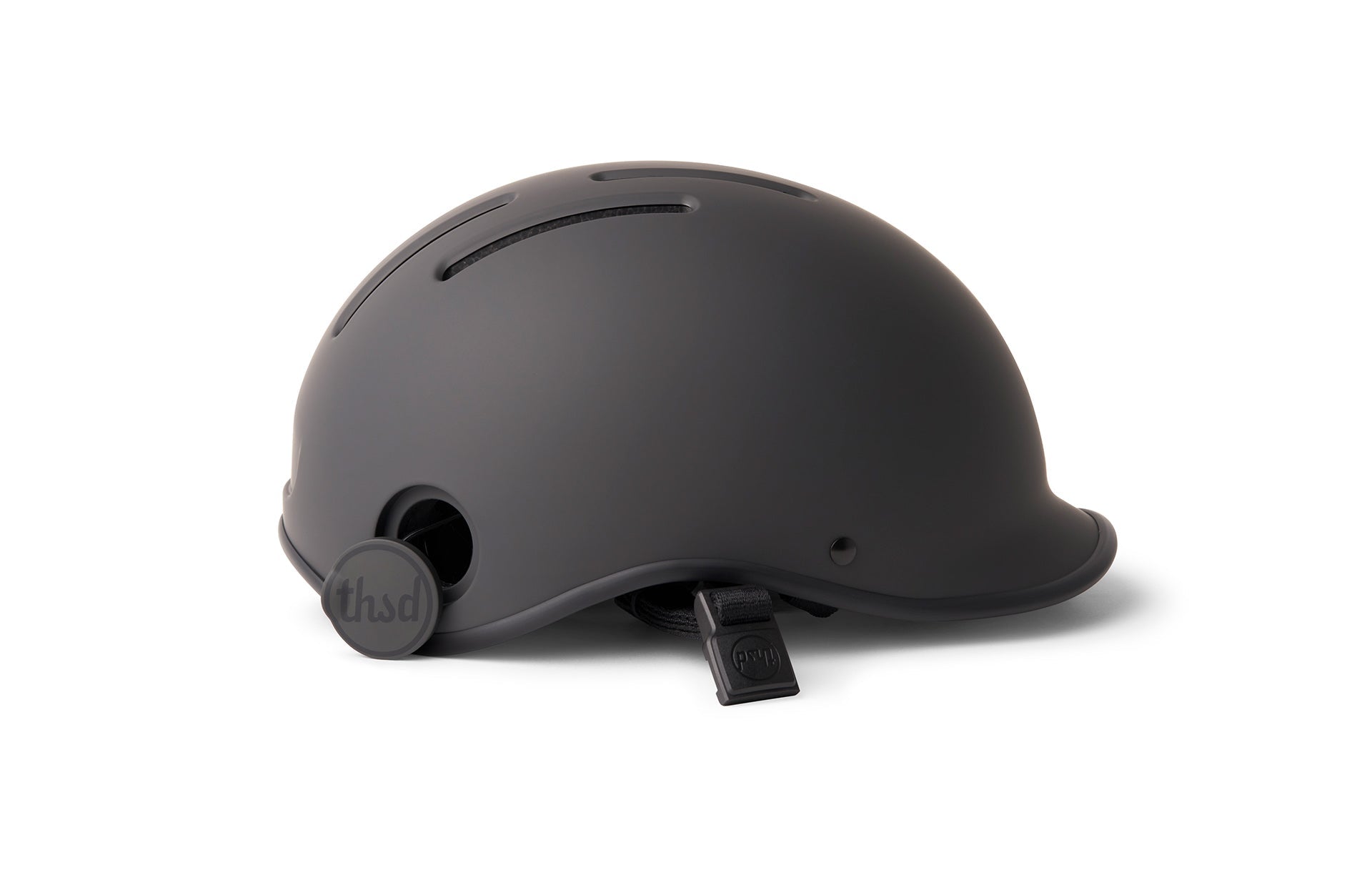 Urban Helmet from The Shade Black with adjustable strap laid flat for image