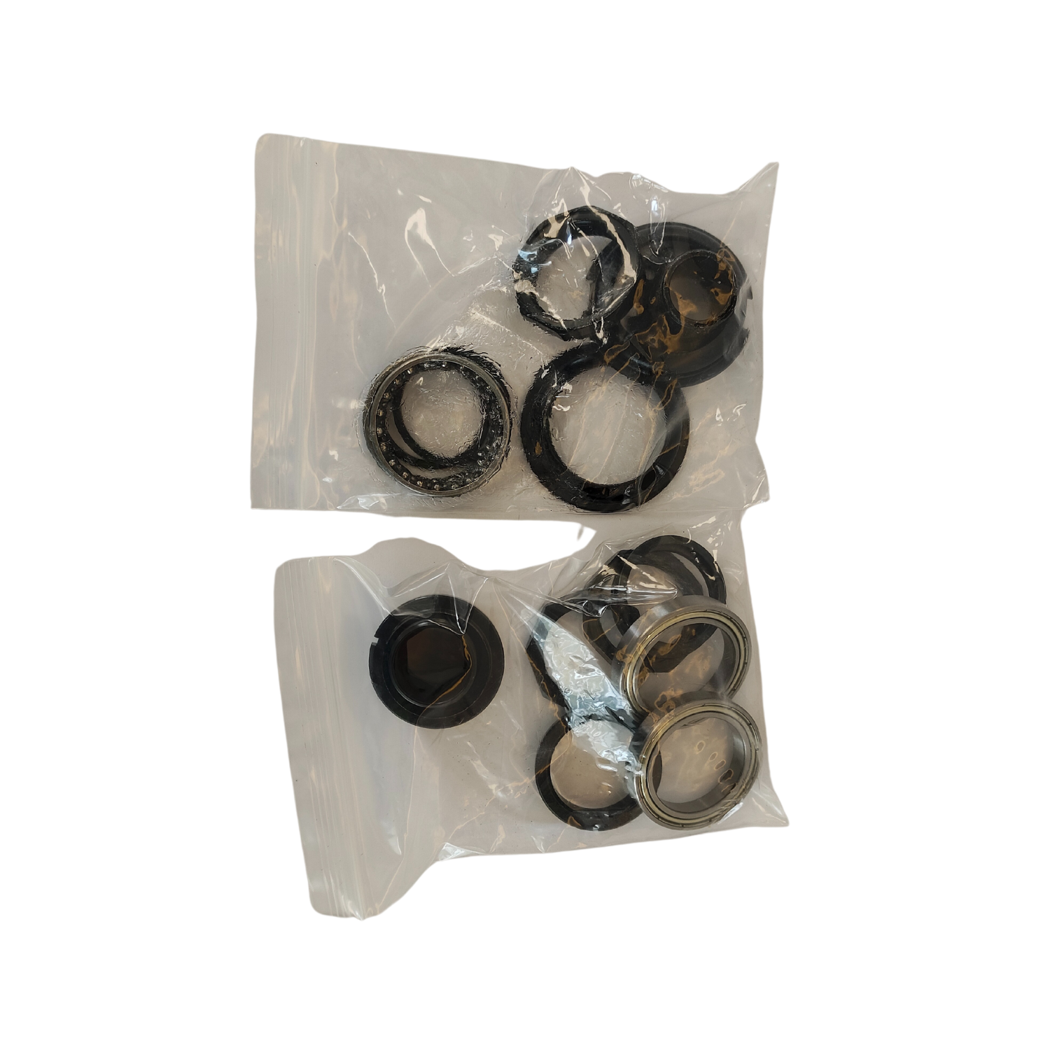 Two clear packs of black grease-filled bearings in an array on a black background