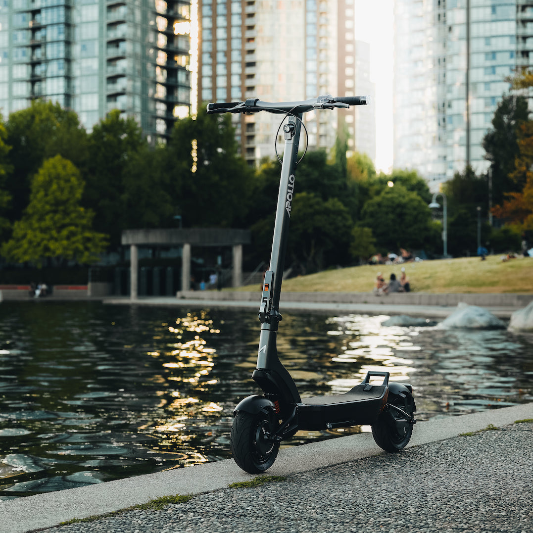 An Apollo City electric commuter scooter parked in a city park and pond area.