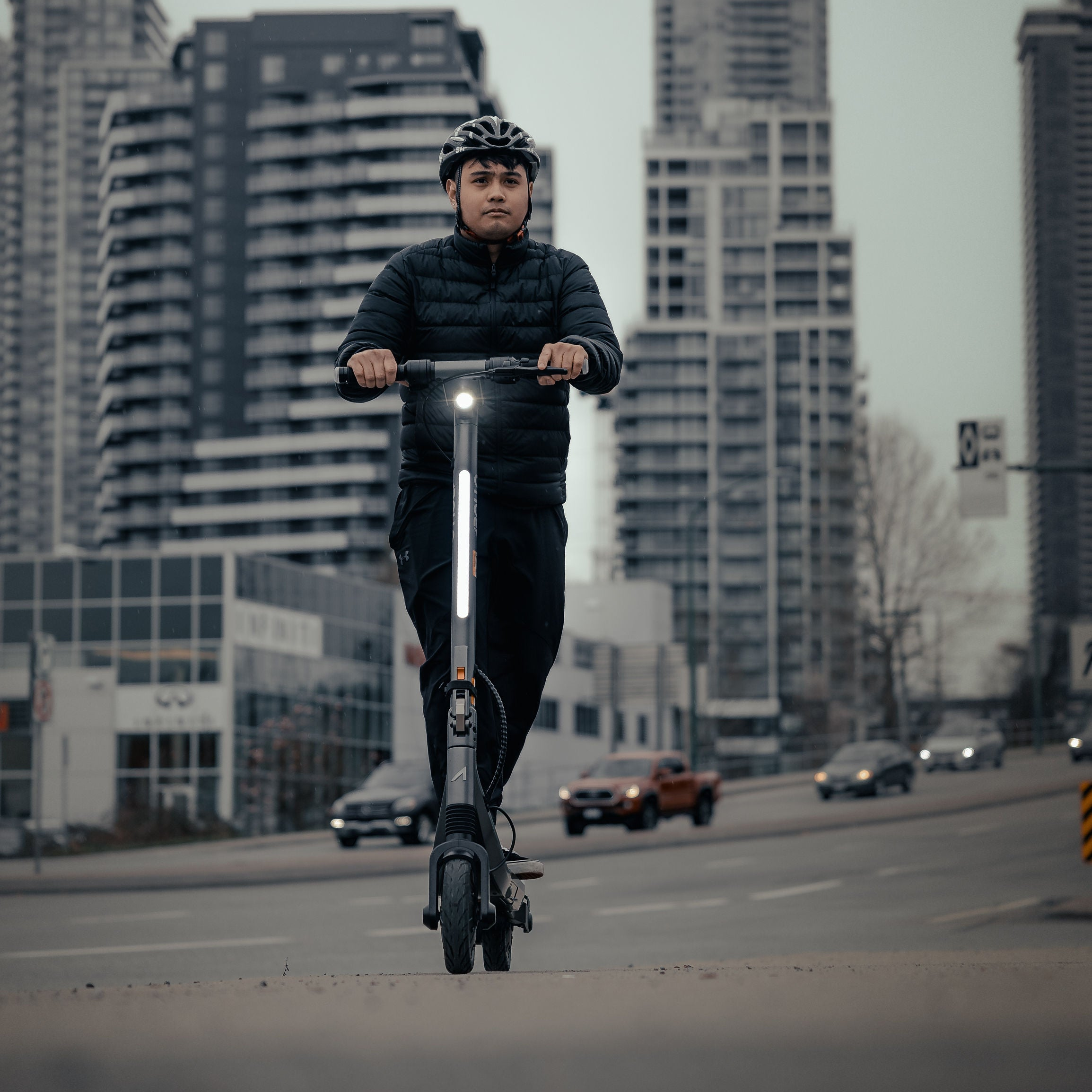 Person riding an Apollo Go electric scooter on a city street with tall buildings in the background