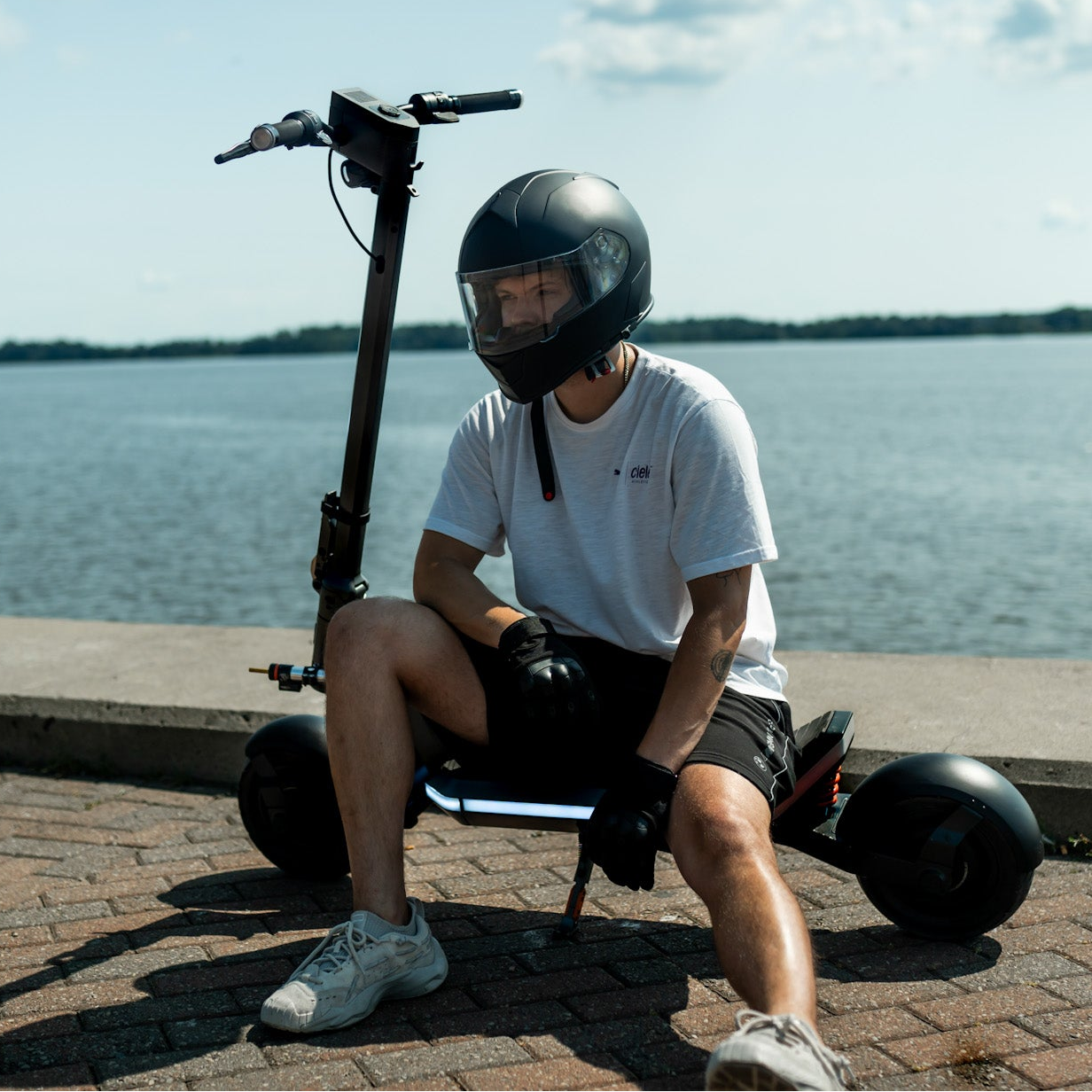 Person sitting on a self-balancing scooter by a waterfront
