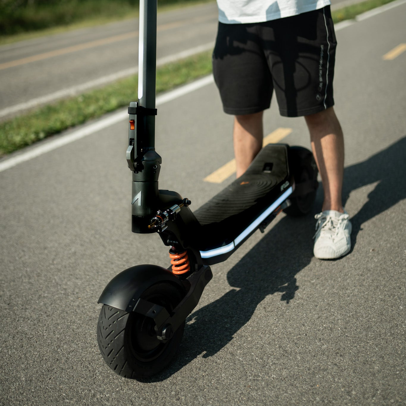 Person standing next to an electric scooter on a road