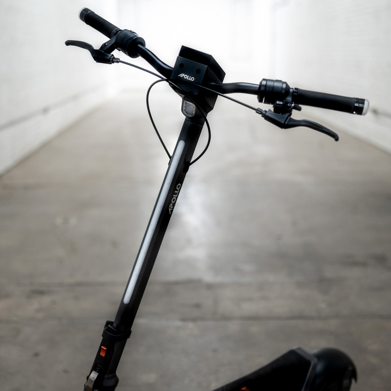 Black scooter handlebar with 'Apollo' branding on a concrete floor.