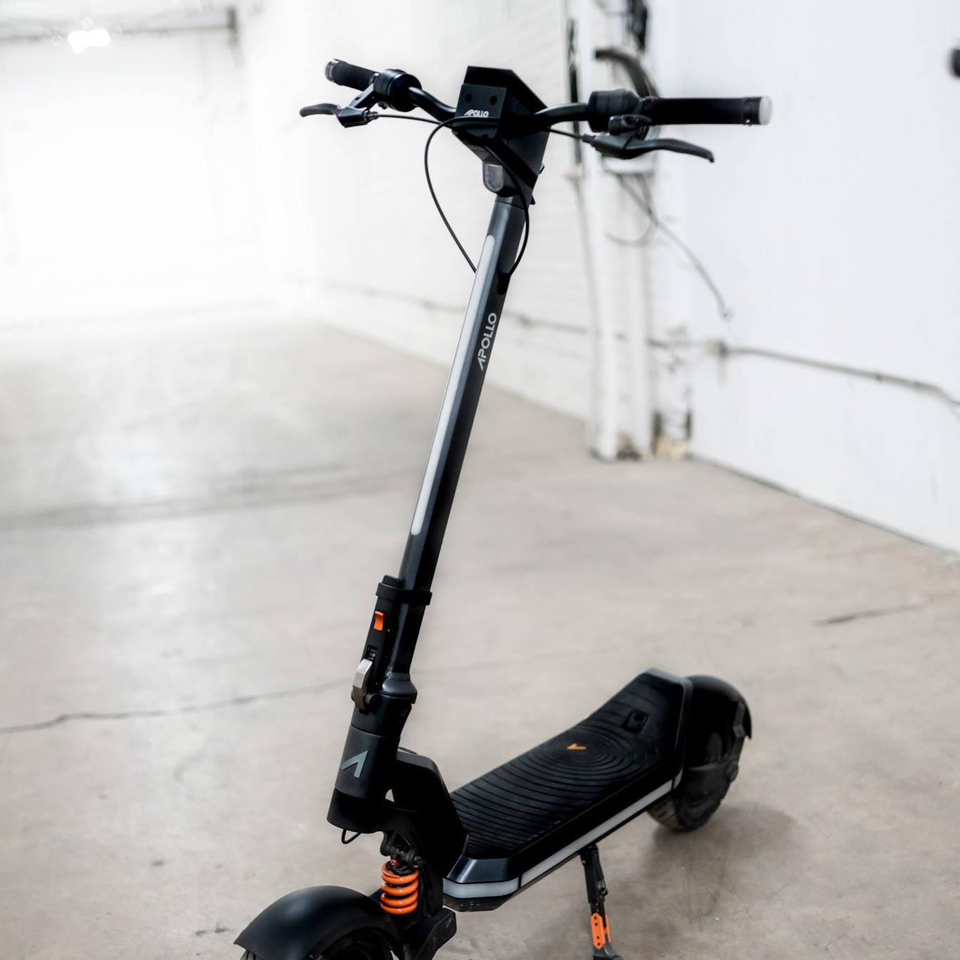 Black electric scooter on a concrete floor with a white wall background