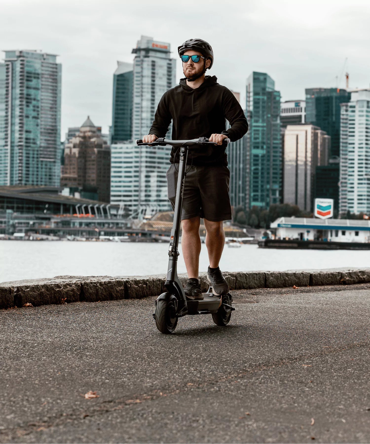 An adult man riding an Apollo Electric Scooter on a city street.