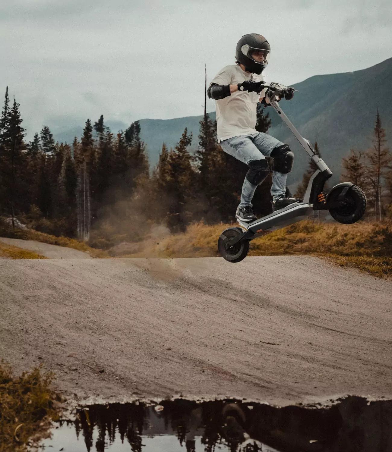 Photo of a young man riding an electric scooter while doing a jump in an outdoor area