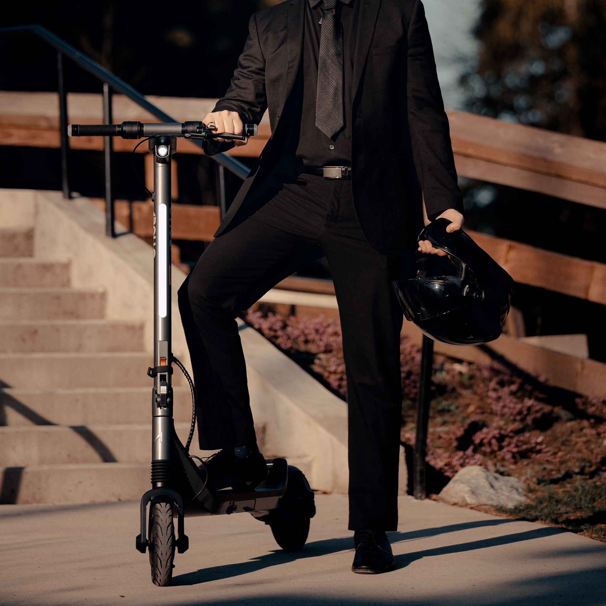 Person in a black suit with a helmet and an Apollo Go scooter outdoors