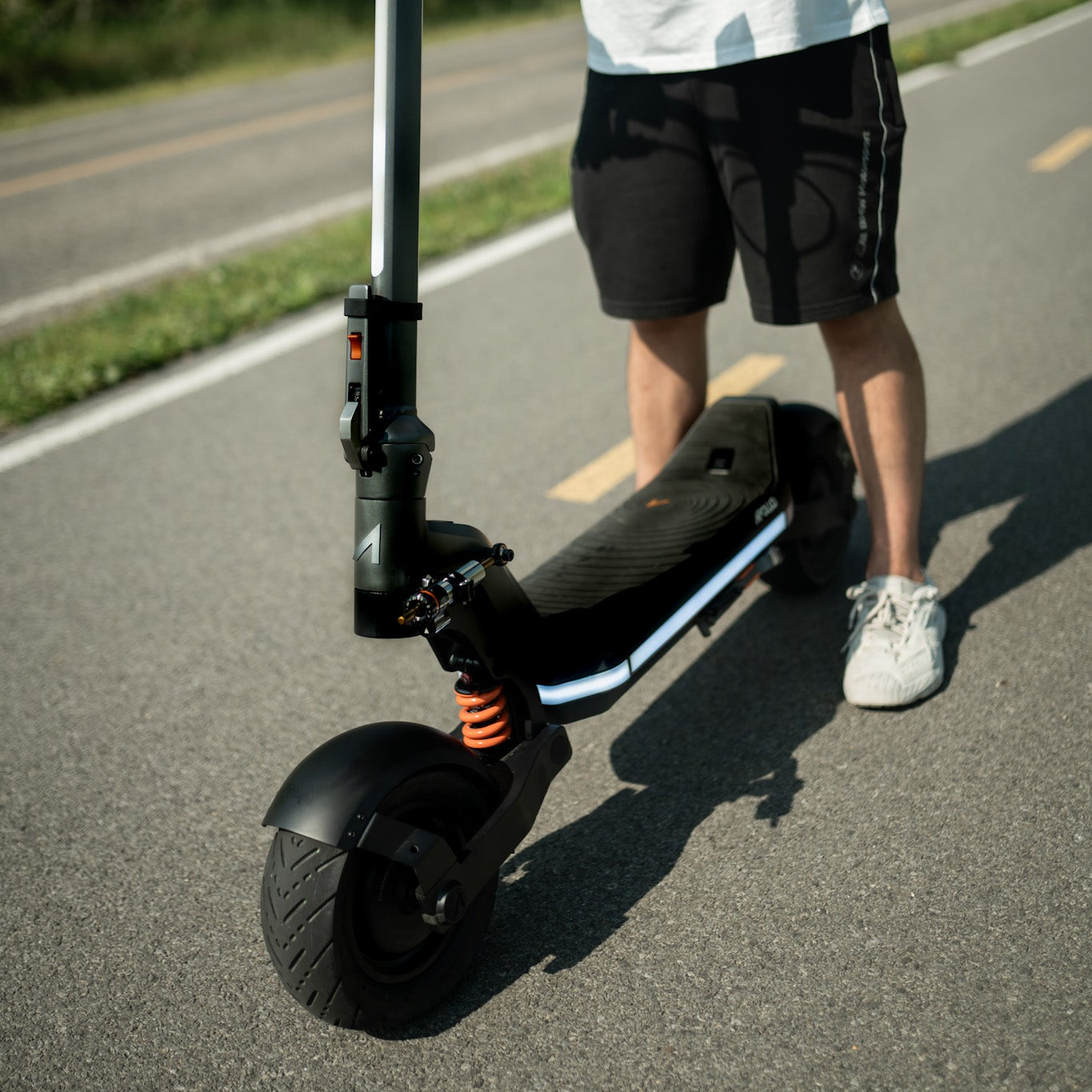 Person standing on a black electric scooter on a road