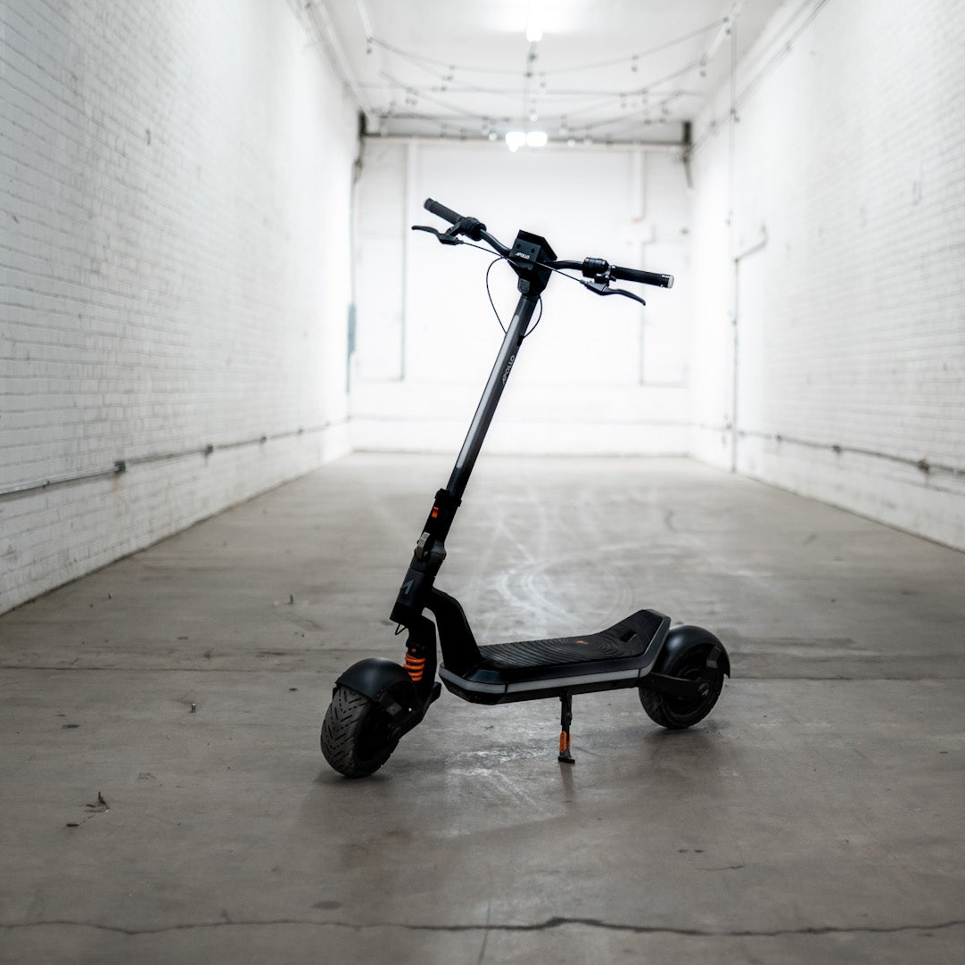 Black electric scooter in a white-walled indoor space